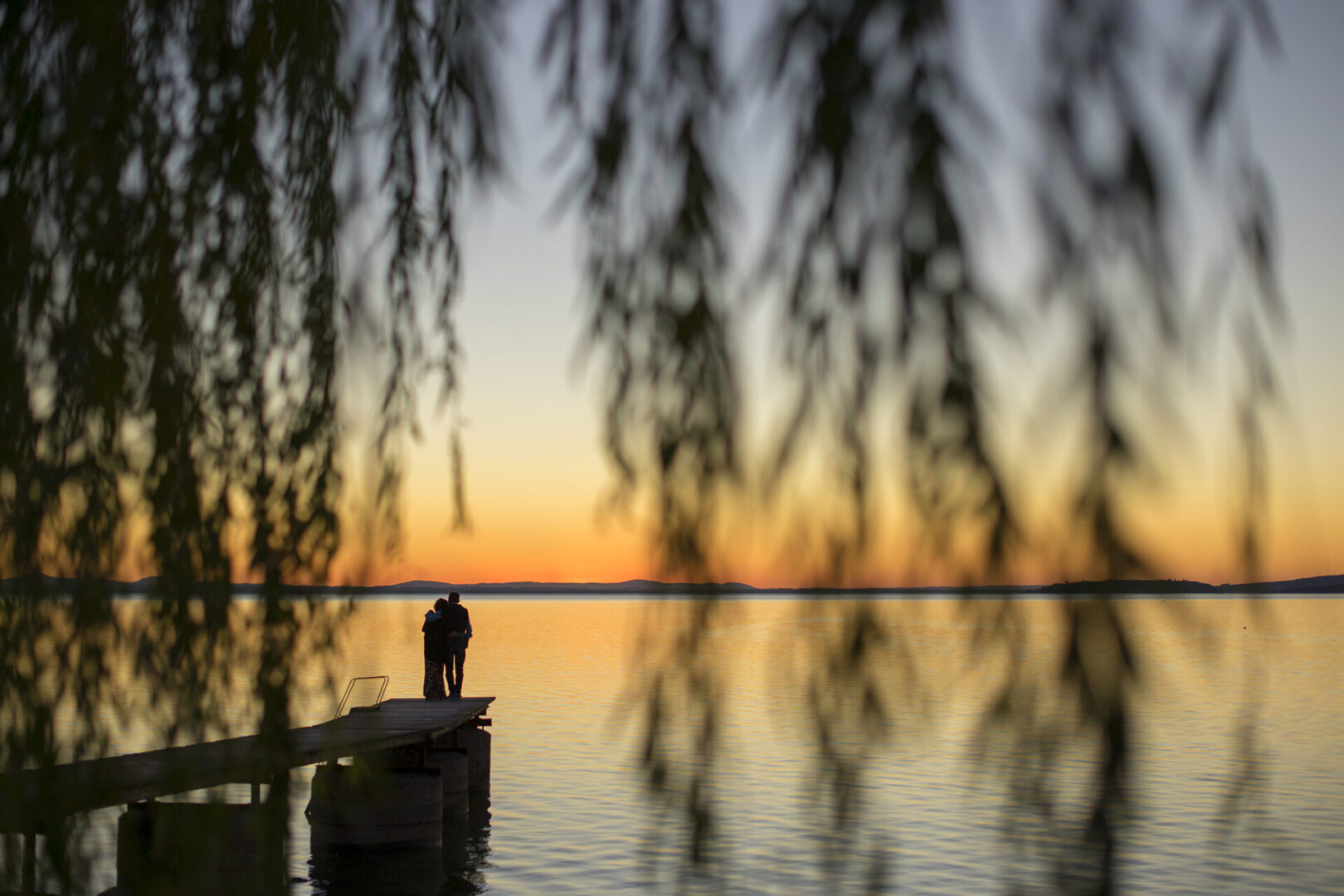 coppia abbracciata sul pontile al tramonto